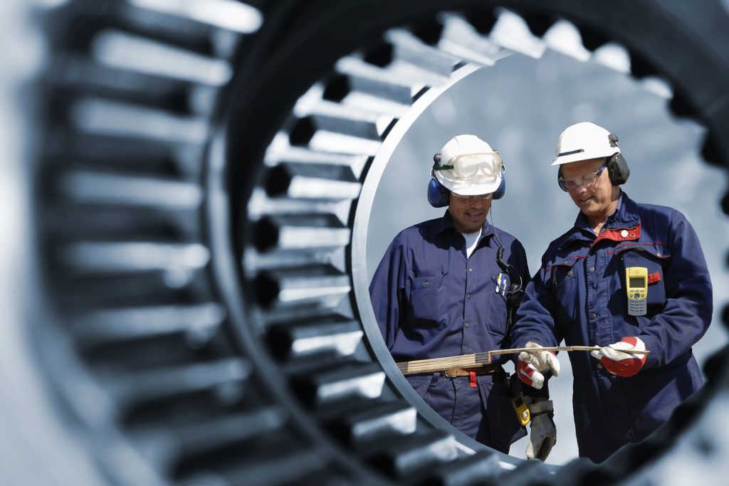 engineers, workers seen through a large cogwheels interior