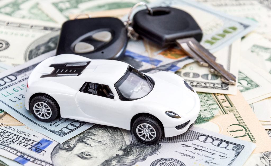 Toy car and keys sitting on pile of money