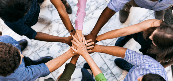 a diverse team of people standing in a circle with their hands in the middle