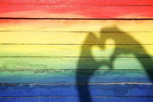 rainbow painted wall with shadow of hands making a heart